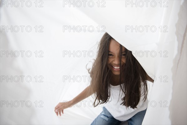 Mixed Race girl playing with curtain