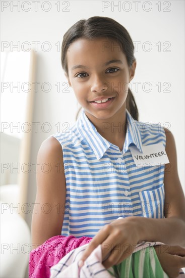 Mixed Race girl volunteering and carrying clothing