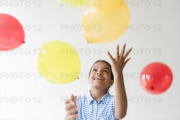 Mixed Race girl throwing balloons