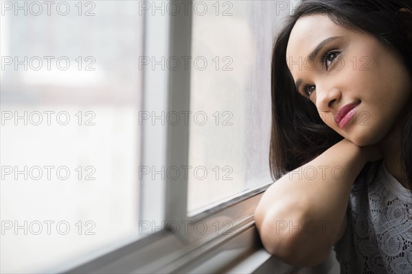 Mixed Race woman daydreaming at window