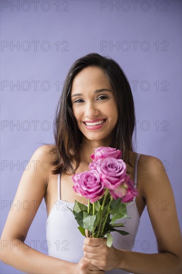 Smiling Mixed Race woman holding bouquet of roses