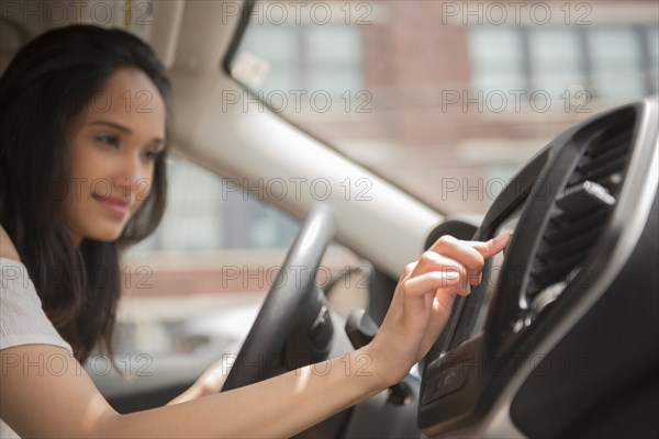 Mixed Race woman pressing touch screen in car