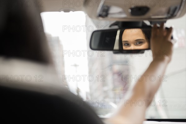 Mixed Race woman adjusting rear-view mirror in car