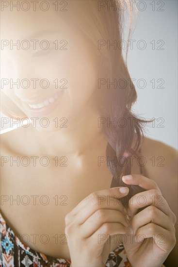 Smiling Mixed Race woman braiding hair