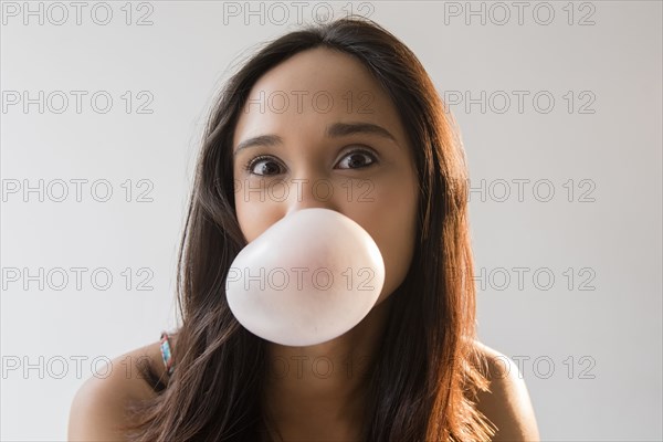 Mixed Race woman blowing bubble with gum