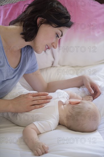 Caucasian mother and baby son laying on bed