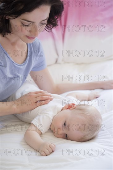 Caucasian mother and baby son laying on bed