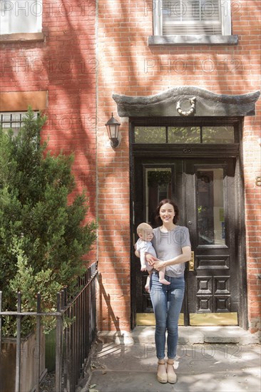 Caucasian mother standing near doorway holding baby son