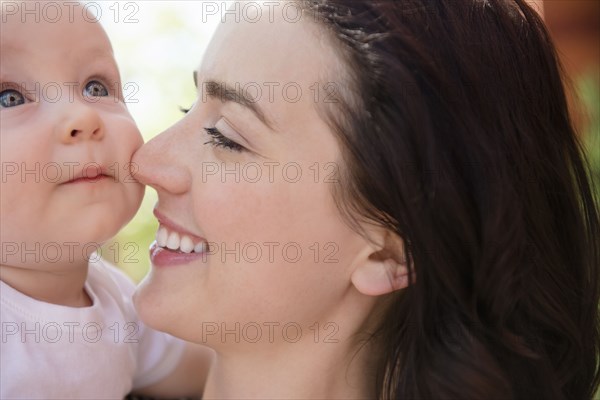 Caucasian mother rubbing nose on cheek of baby son