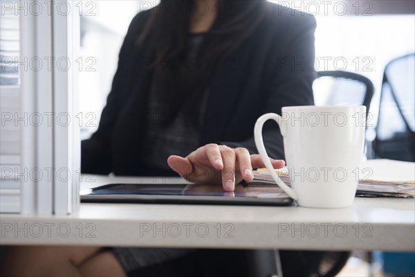 Mixed Race businesswoman using digital tablet in office