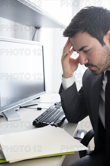 Businessman with headache at office desk