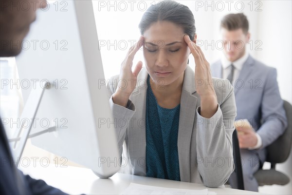Businesswoman with headache rubbing temples in office