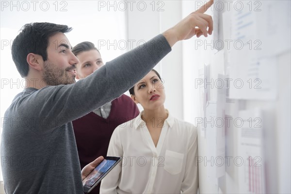 Business people talking about paperwork on wall