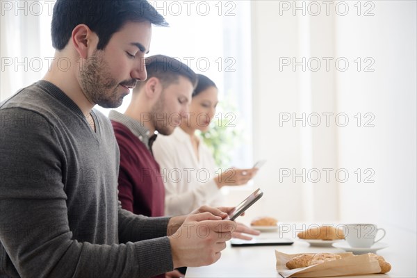 Business people using technology at breakfast table