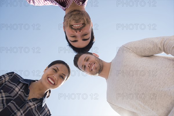 Smiling friends losing under blue sky