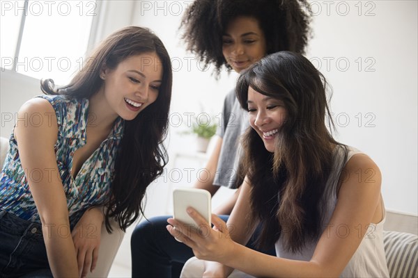 Smiling women texting on cell phone in livingroom
