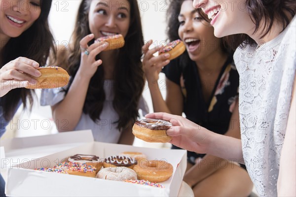 Smiling women eating donuts