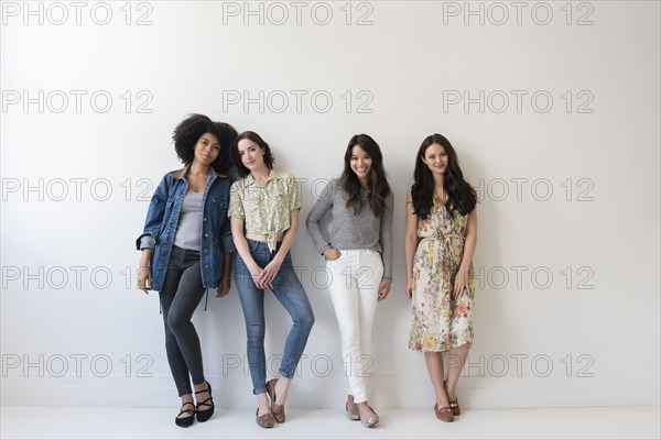 Portrait of smiling women leaning on wall