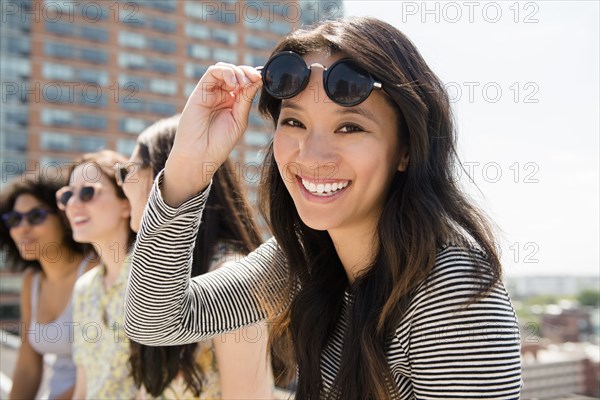 Smiling woman lifting sunglasses outdoors