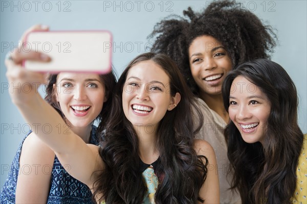 Smiling women posing for cell phone selfie