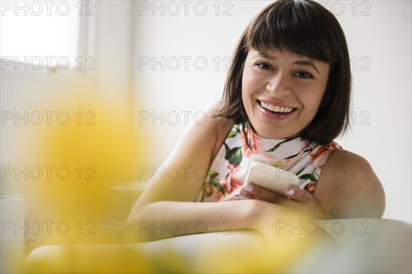 Portrait of smiling Hispanic woman holding cell phone