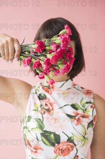 Hispanic woman wearing floral dress holding flowers