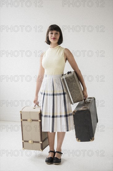Portrait of smiling Hispanic woman holding suitcases