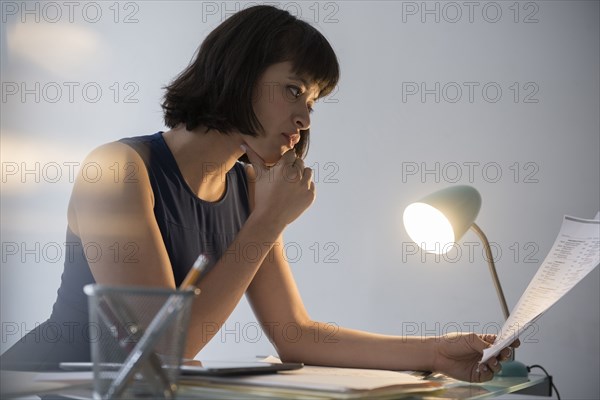 Hispanic businesswoman working late reading paperwork