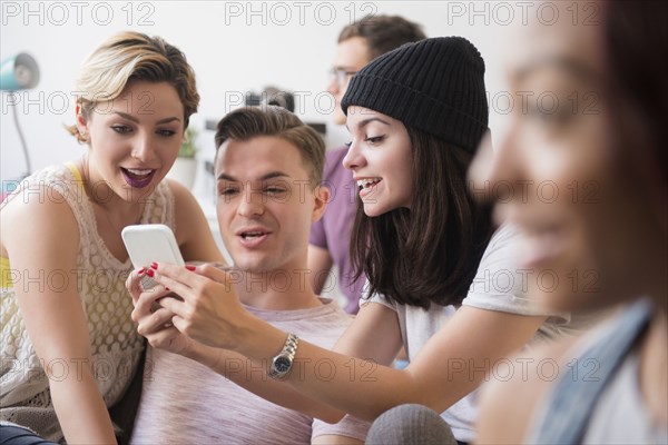 Smiling friends texting on cell phone