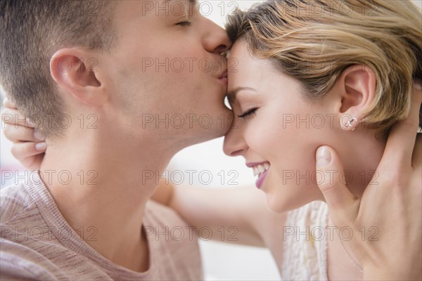 Caucasian man kissing girlfriend on forehead