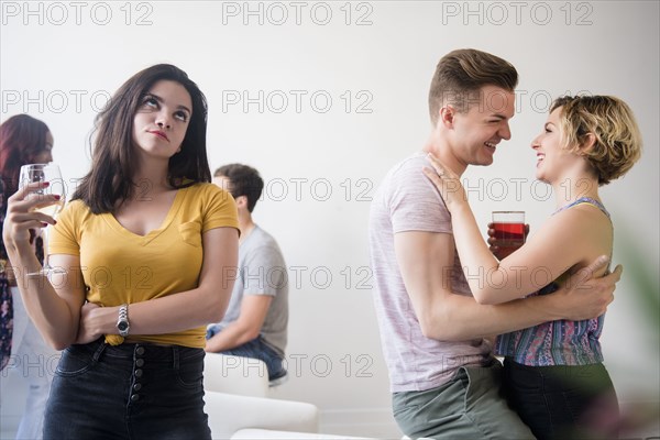 Woman at party rolling eyes at affectionate couple