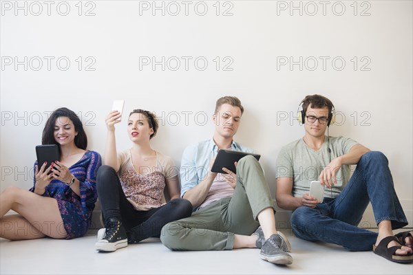 Caucasian friends sitting on floor using technology