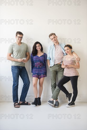 Portrait of smiling Caucasian friends leaning on wall