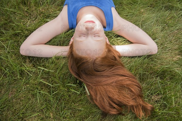 Caucasian girl laying in grass with hands behind head