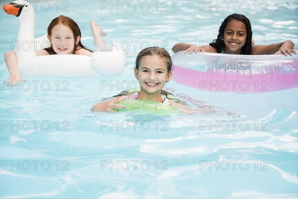 Portrait of smiling girls floating in swimming pool