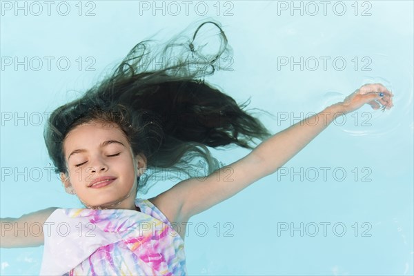 Smiling Caucasian girl floating in swimming pool