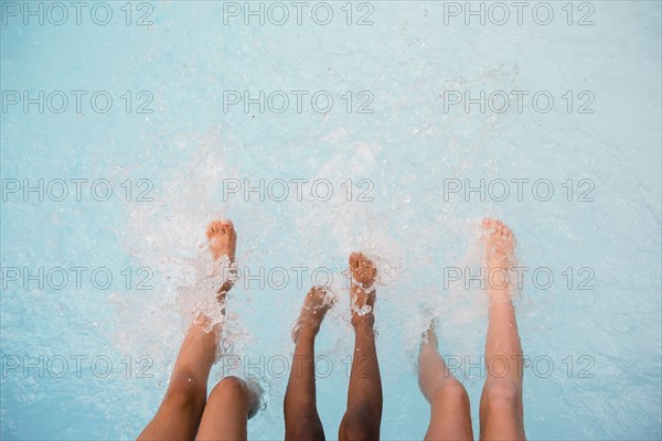 Legs of girls splashing feet in swimming pool