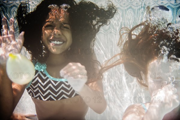 Girls swimming and waving underwater