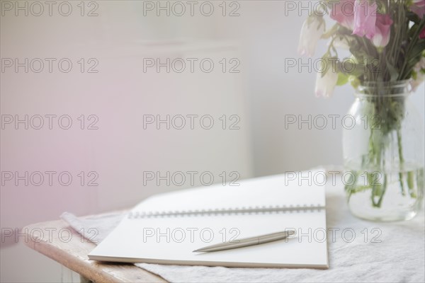 Pen on open blank notebook near flowers