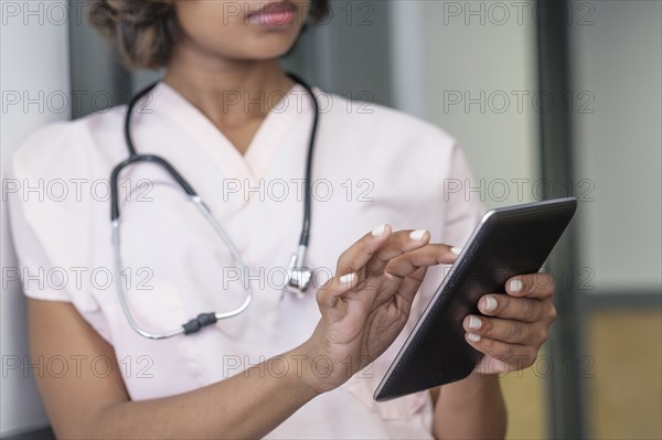 Mixed Race nurse using digital tablet