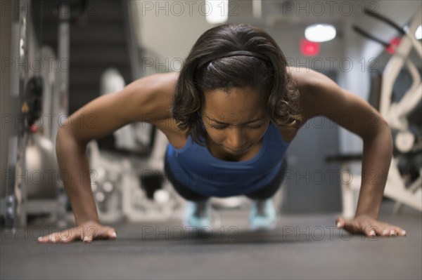 Mixed Race woman doing push-up on floor at gymnasium