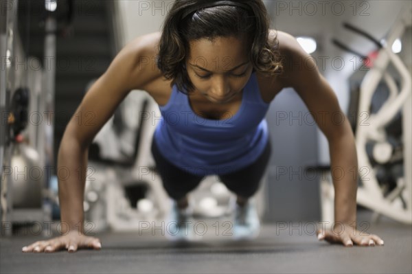 Mixed Race woman doing push-up on floor at gymnasium
