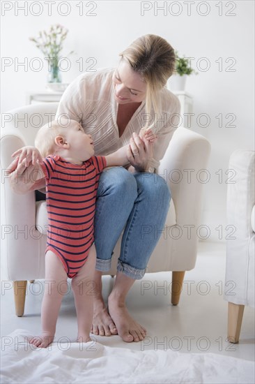 Caucasian mother helping standing baby son