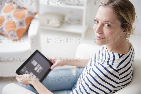 Caucasian woman sitting in armchair using digital tablet