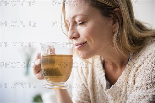 Caucasian woman smelling cup of tea