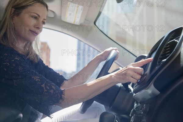 Caucasian woman using touch screen on dashboard of car