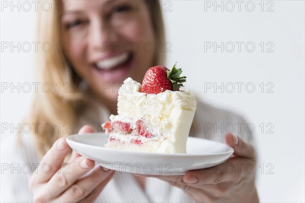 Caucasian woman holding slice on vanilla cake with strawberry