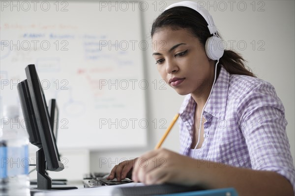 Hispanic woman in computer lab writing in notebook
