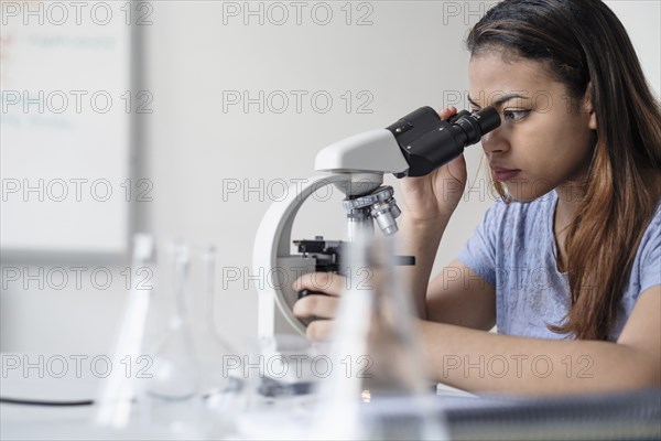 Hispanic woman using microscope