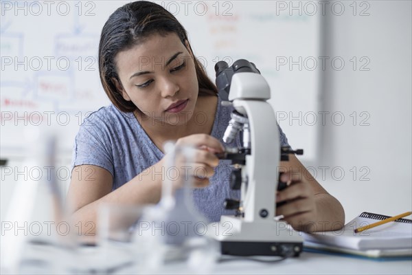 Hispanic woman adjusting microscope